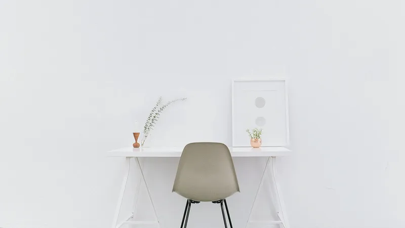 Small white desk and chair against a plain wall in a bright room