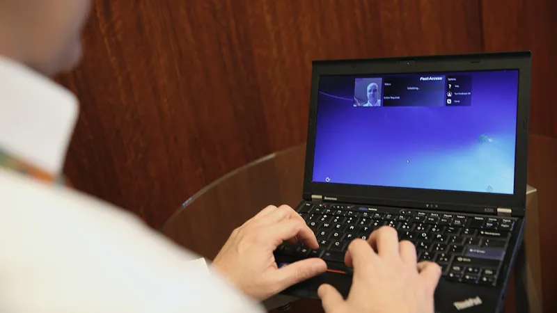 Hands typing at a laptop showing a sign-in screen