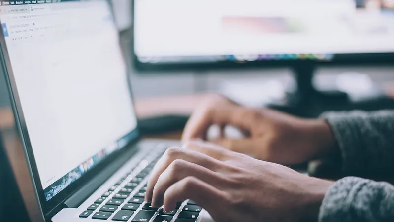 Hands typing on a laptop keyboard at a desk