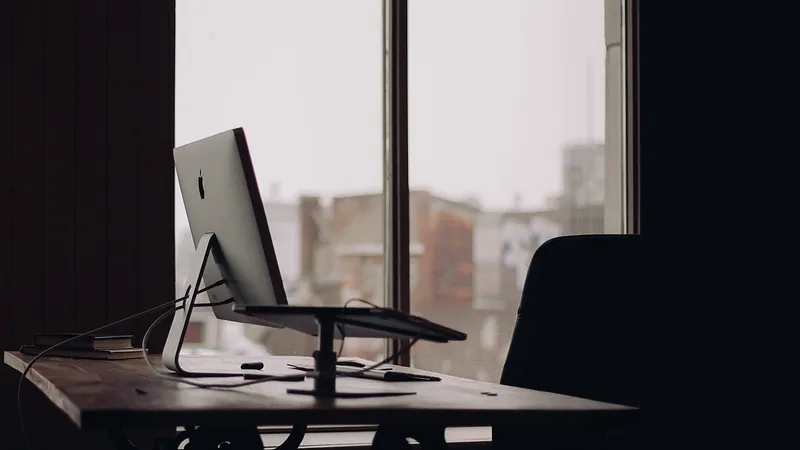 Desktop monitor sitting dark on a desk by a window
