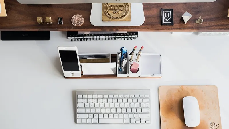 Keyboard, phone and mouse laid out on a wooden desk